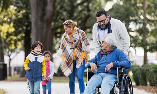 A multi-generational family is walking through the park together