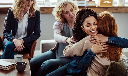 Two members of a family hug each other in a therapist's office