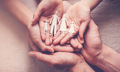 Closeup of a parent and child's hands holding a paper-cutout family