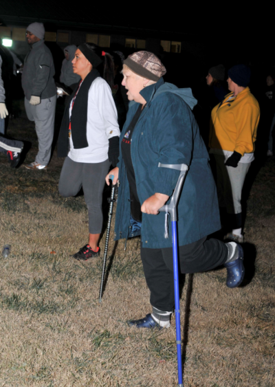 An older woman on crutches participates in a team field training.